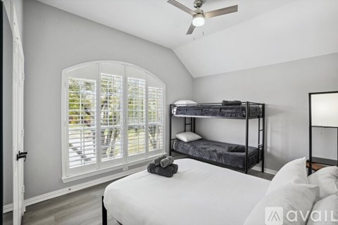 A bedroom with a bunk bed and a window with shutters.