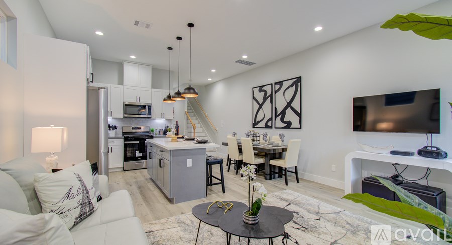 A living room with a white couch and a TV on the wall.