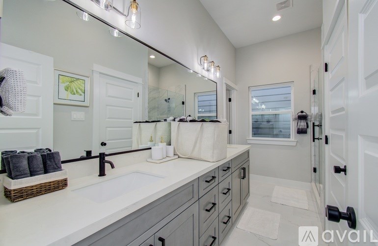 A bathroom with a sink, mirror, and a basket of towels.