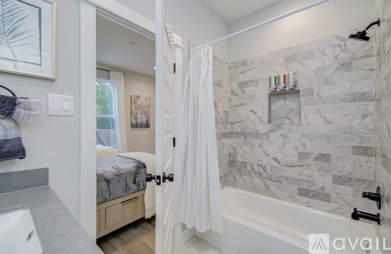 A bathroom with a marble tile wall and a white shower curtain.