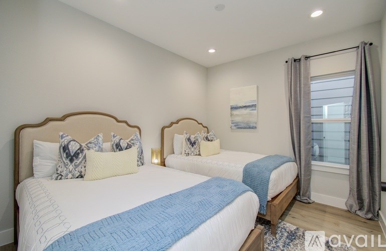 Two twin beds with blue bedspreads in a room with white walls.