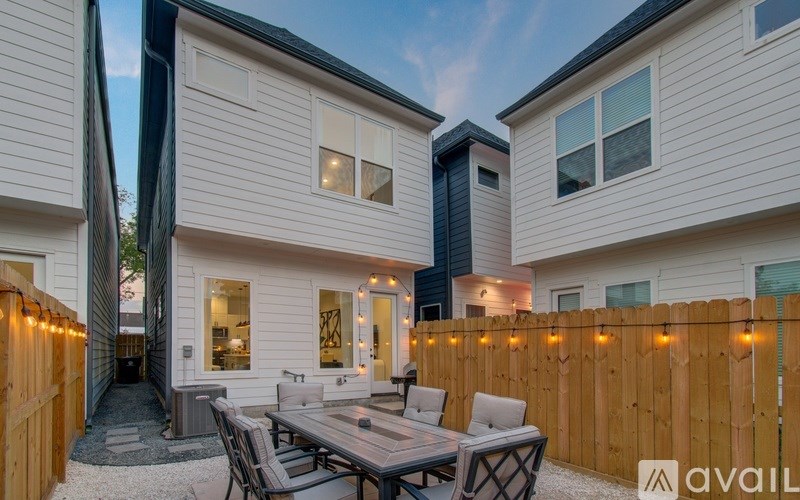 A modern house with a wooden fence and a dining table set up outside.