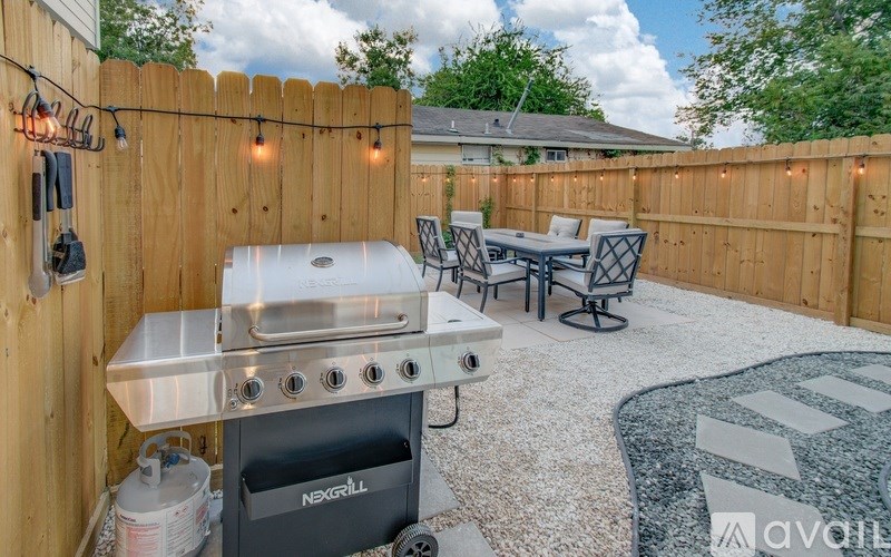 A backyard with a grill and chairs.