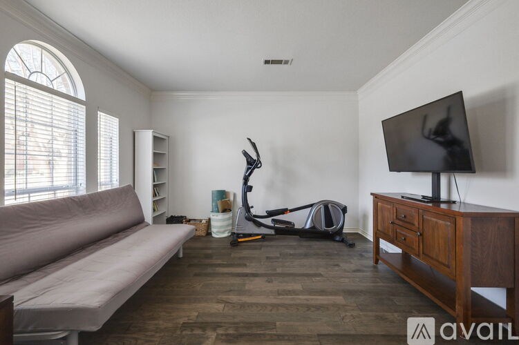 A living room with a grey sofa, a television, and a wooden cabinet.