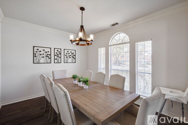 A dining room with a wooden table and white chairs.