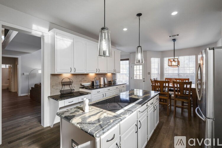 A kitchen with a marble countertop and white cabinets.