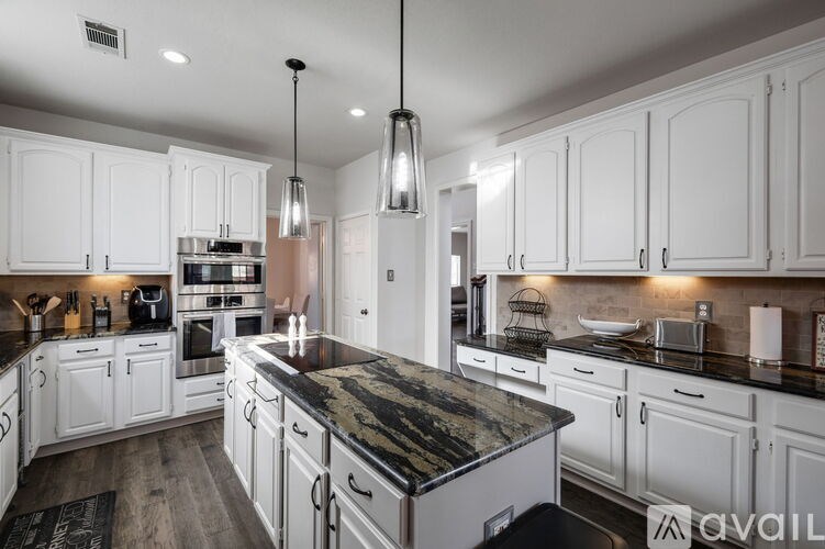A kitchen with white cabinets and a black countertop.