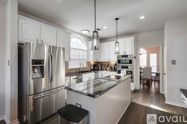 A modern kitchen with stainless steel appliances and white cabinetry.