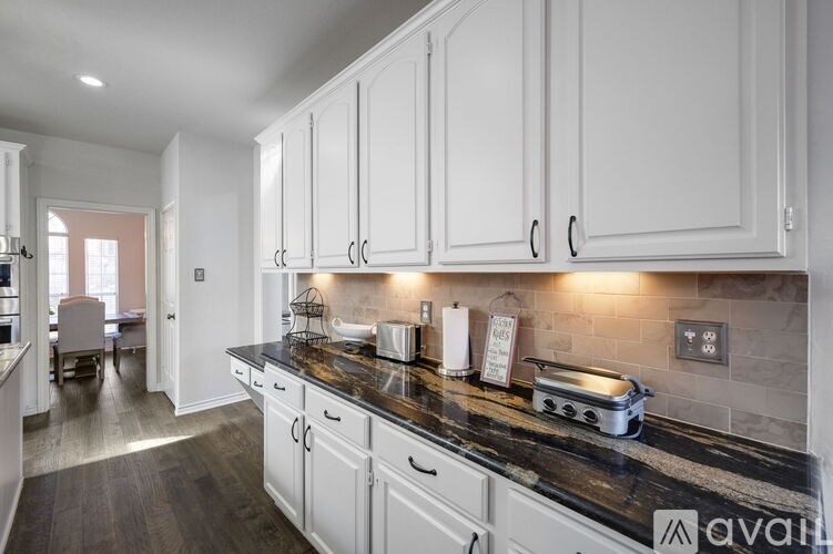 A kitchen with white cabinets and a black countertop.
