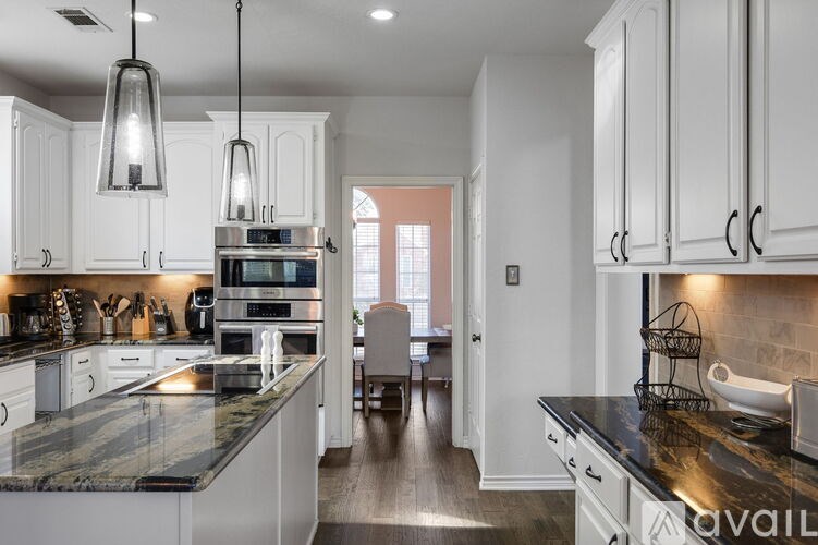 A modern kitchen with white cabinets and a black countertop.