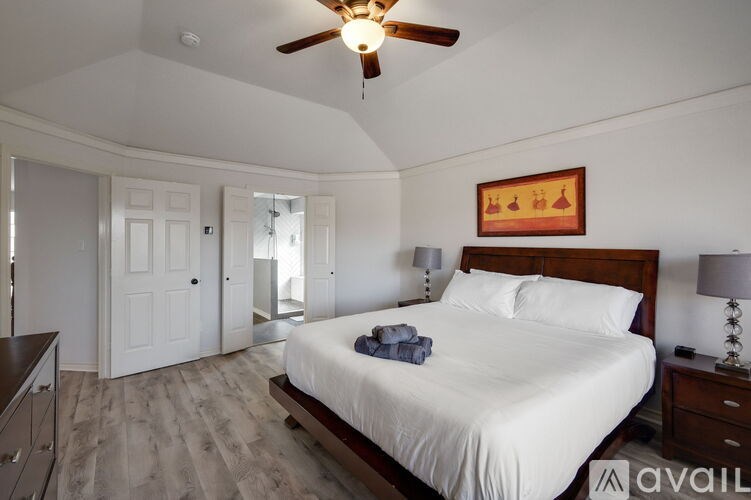 A bedroom with a bed, dresser, and ceiling fan.