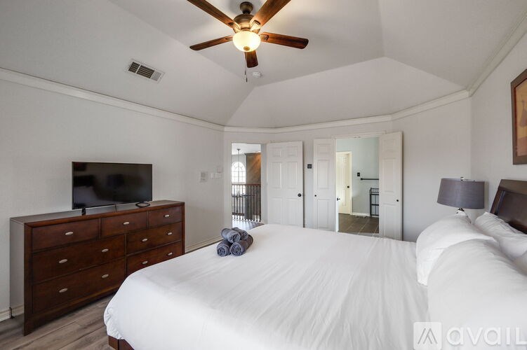 A bedroom with a large bed, a ceiling fan, and a television.