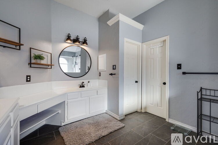 A bathroom with a white countertop and a round mirror above it.