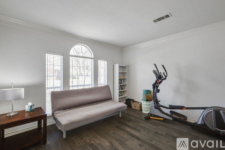 A living room with a couch, a table, a window, and a vacuum cleaner.