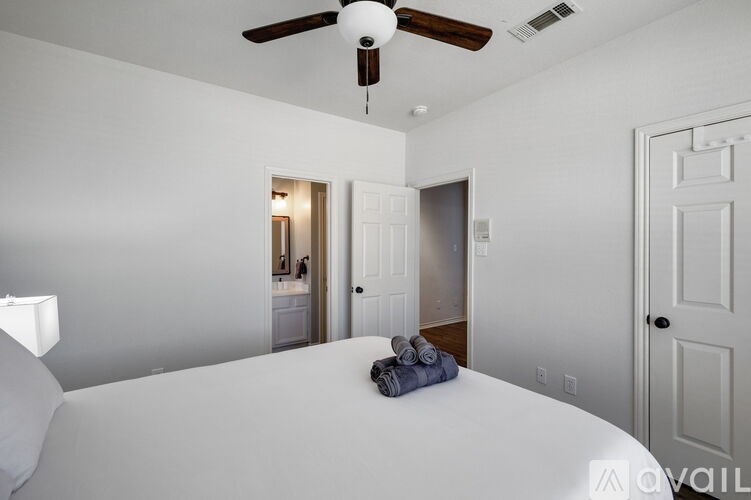 A bedroom with a bed, a ceiling fan, and a door.