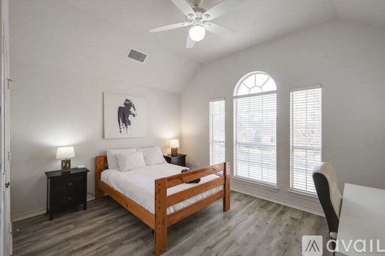A bedroom with a bed, two lamps, and a painting on the wall.