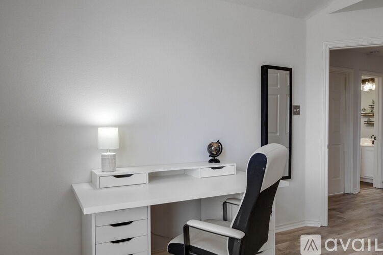 A white desk with a black chair and a lamp on it.