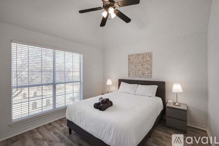 A bedroom with a bed, two lamps, and a ceiling fan.
