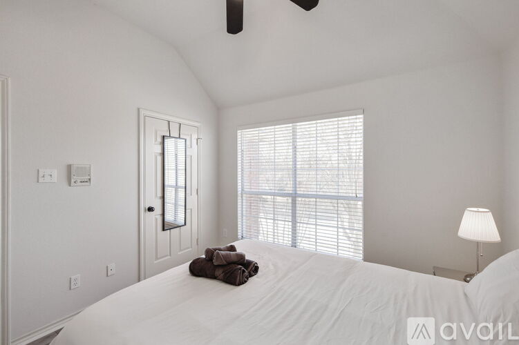A bedroom with a large bed and a window with blinds.