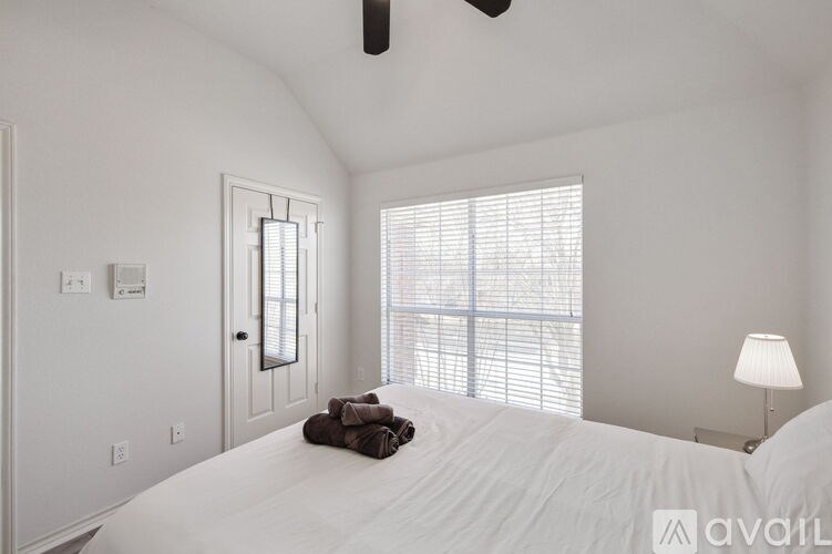 A bedroom with a large bed and a window with blinds.