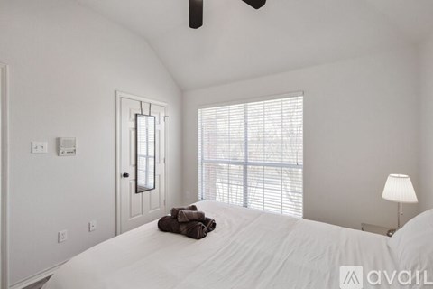 A bedroom with a large bed and a window with blinds.