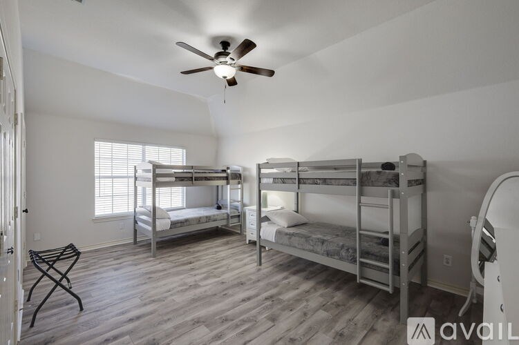 A room with two bunk beds and a ceiling fan.