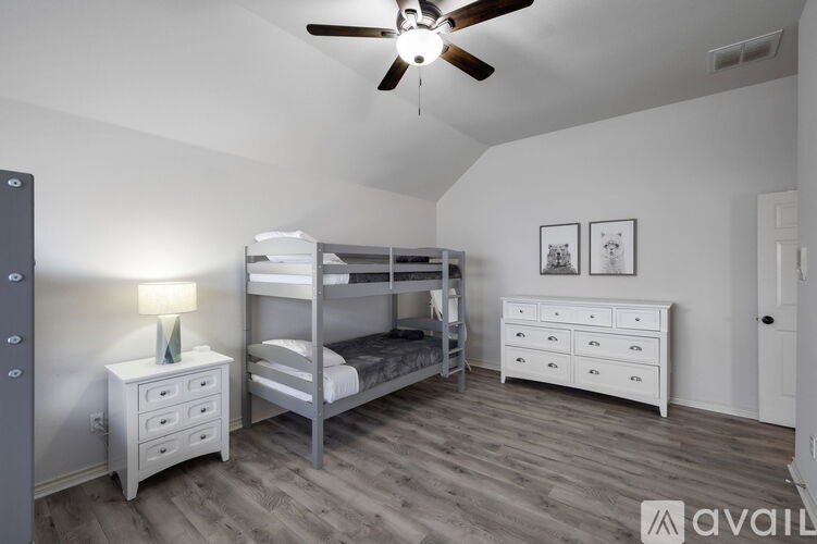 A room with a bunk bed, a dresser, and a nightstand with a lamp.