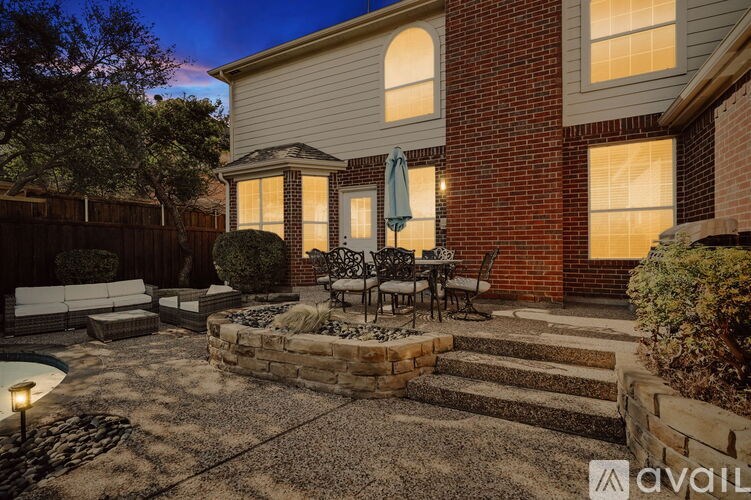 A backyard with a patio, a fire pit, and a brick wall.