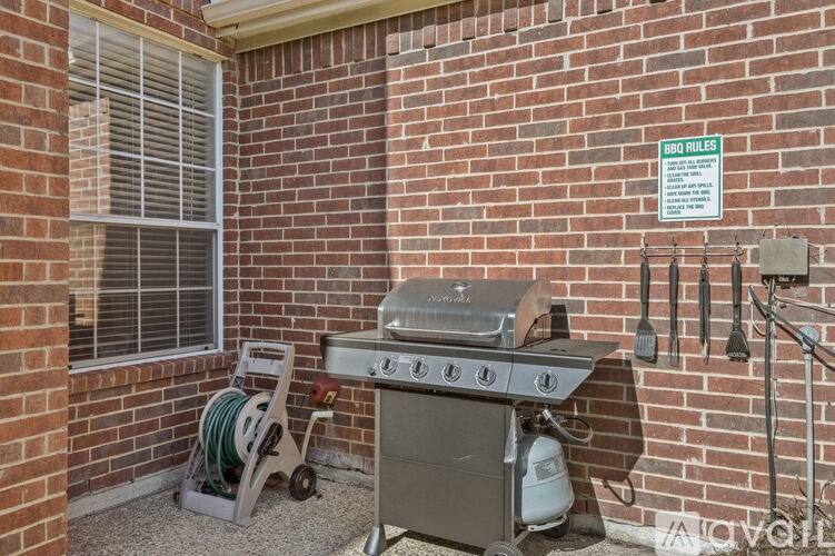 A BBQ grill is set up on a patio with a sign that reads "BBQ RULES".