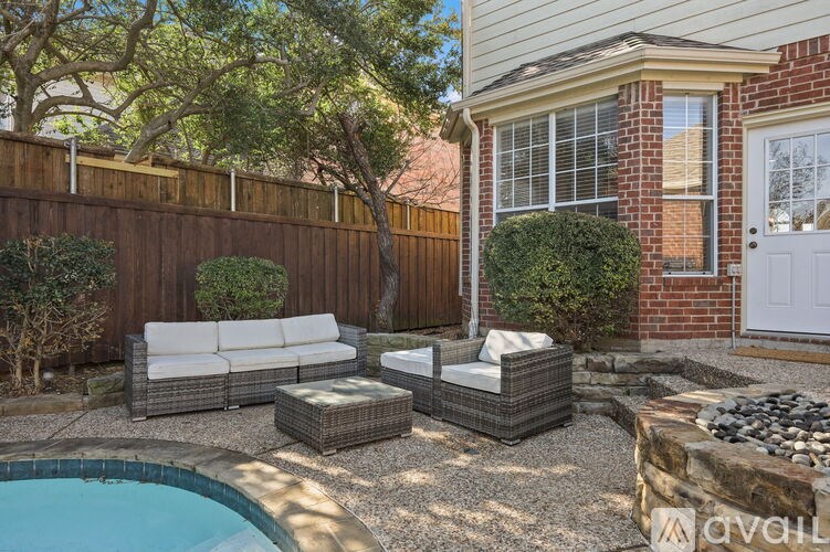 A backyard with a pool, patio furniture, and a wooden fence.