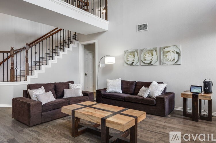 A living room with a brown couch, a wooden coffee table, and a staircase.