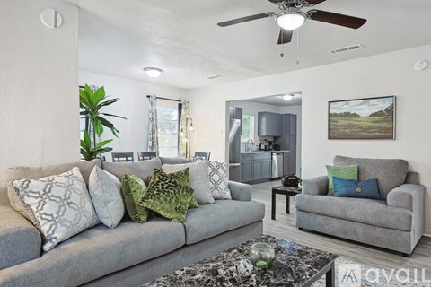 A living room with a grey couch, a coffee table, and a ceiling fan.