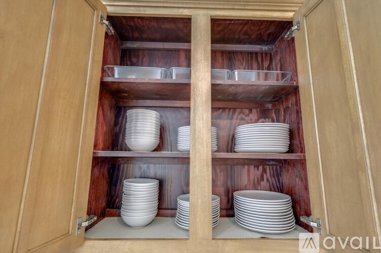 A wooden cabinet with plates stacked on shelves.