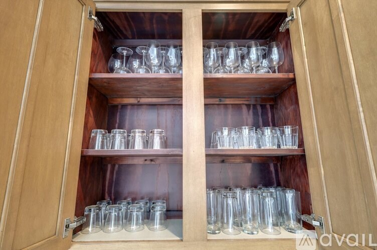 A cabinet is open with two shelves holding glasses.