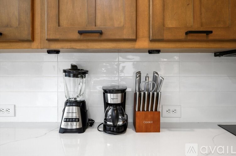 A kitchen counter with a blender, coffee maker, and a knife block.