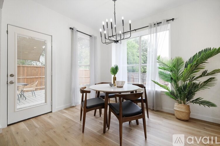 A dining room with a table set for two and a potted plant.