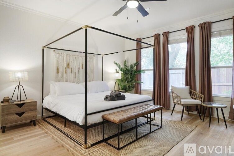 A bedroom with a four poster bed and a chair.