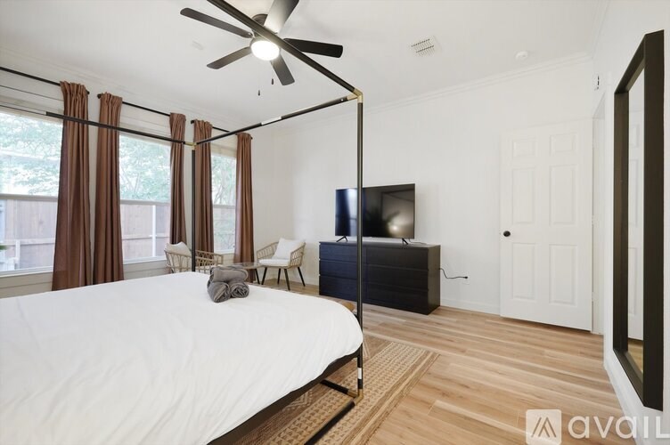A bedroom with a large bed, a ceiling fan, and a television.