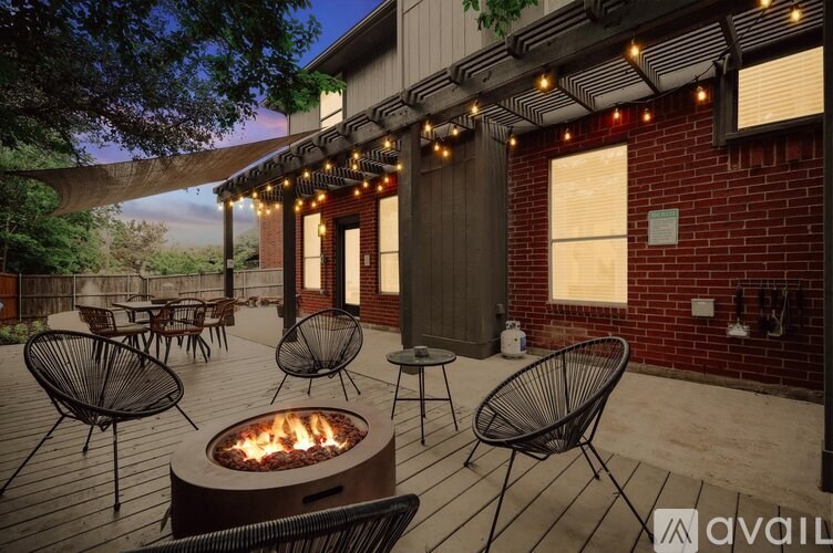 A patio with a fire pit and chairs.