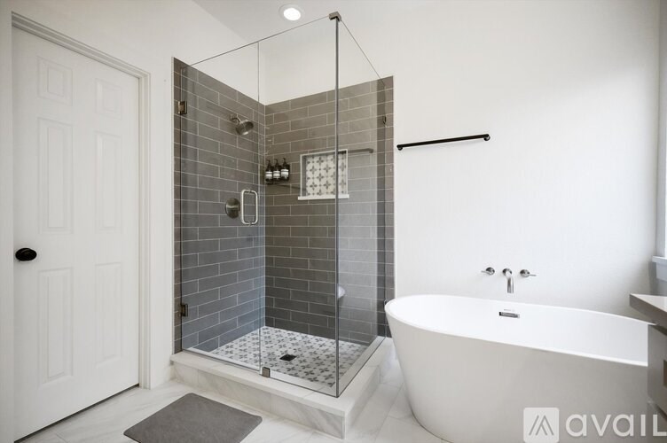 A bathroom with a white tub and a glass shower door.