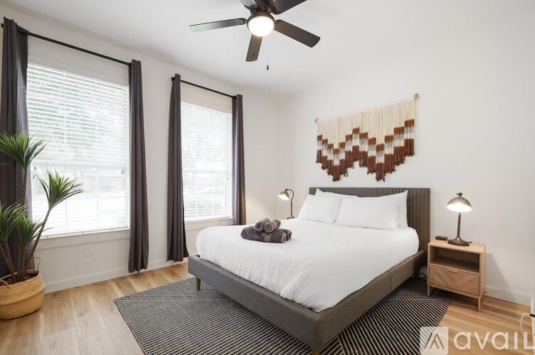 A bedroom with a large bed, a ceiling fan, and a window with blinds.
