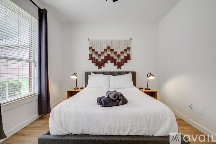 A bedroom with a large bed and a window with blinds.