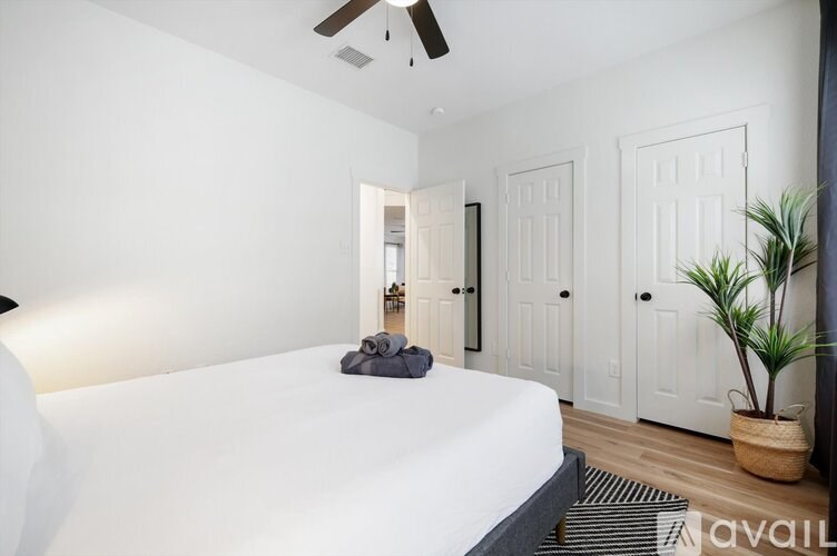 A bedroom with a bed, a ceiling fan, and a plant.