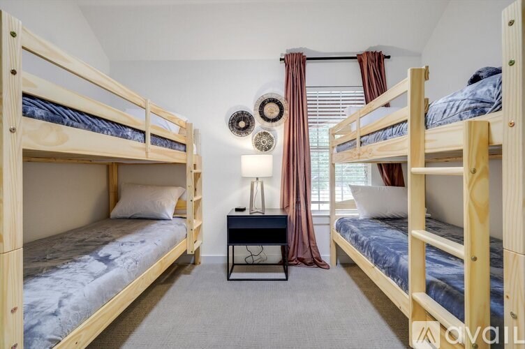 A room with two bunk beds and a small table with a lamp on it.