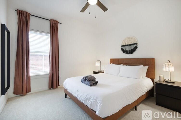 A bedroom with a large bed, a ceiling fan, and a window with curtains.