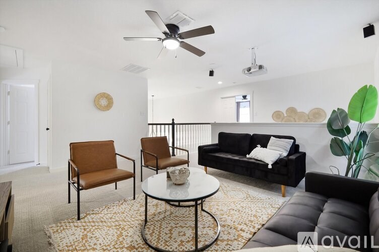 A living room with a black couch, a coffee table, and a ceiling fan.