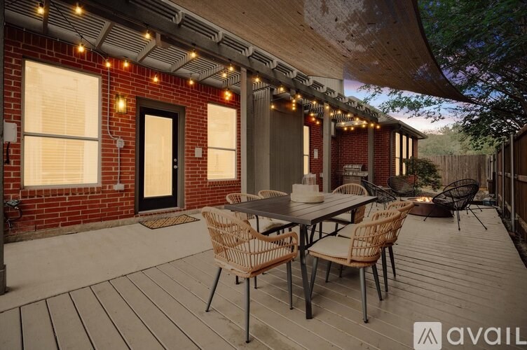 A patio with a table and chairs is set up on a wooden deck.