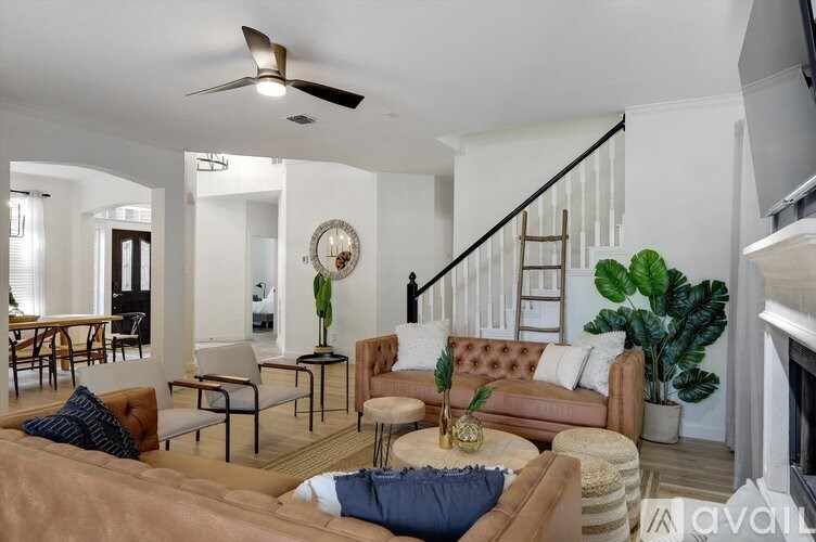 A living room with a brown couch and a ceiling fan.
