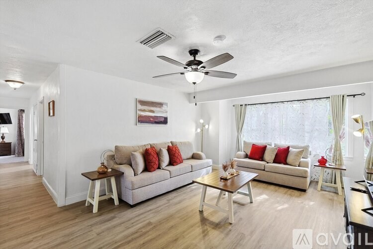 A living room with a white couch, a wooden coffee table, and a ceiling fan.