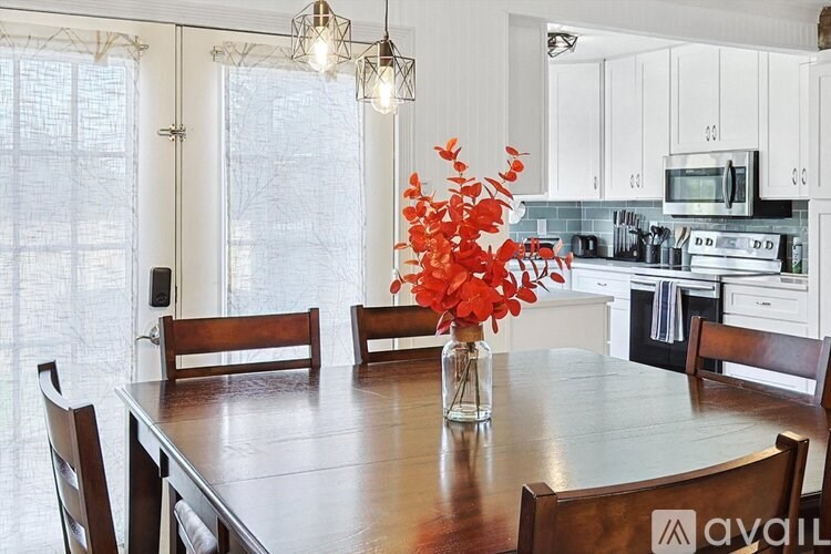 A kitchen with a table and chairs and a vase of flowers.